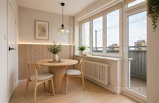 Světlá jídelna s dřevěným nábytkem, velká okna a moderní výzdoba, světlé parketové podlahy dodávají vzdušnost a eleganci prostoru.