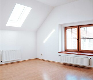 Světlá ložnice s parketovou podlahou, velkými okny a moderním střešním oknem, poskytující dostatek přirozeného světla, vynikající stav