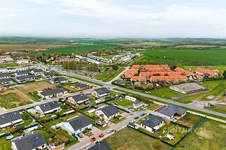 Letecký pohled na rezidenční oblast s moderními rodinnými domy, dobře udržovanými zahradami a zelenými plochami, ideální pro klidné bydlení v přírodě.