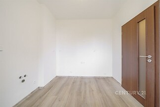 Prázdná místnost s parketovou podlahou, dřevěnými dveřmi a světlými stěnami vhodná pro vlastní úpravy nebo rekonstrukci