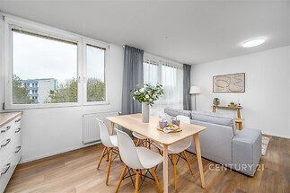 Světlý obývací pokoj s moderní parketovou podlahou a velkými okny, které zajišťují dostatek přirozeného světla, v nově rekonstruovaném stylu.