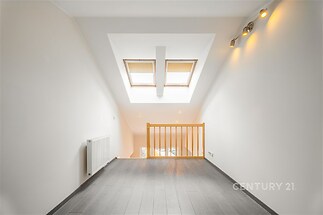 Podkrovní prostor s moderní dlažbou, dřevěnými střešními okny a vestavěným osvětlením, ideální pro světlou a vzdušnou kancelář nebo ateliér.