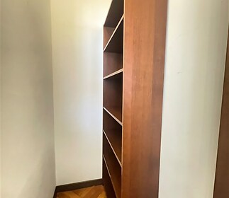 Úzká chodba s dřevěnou knihovnou, parketová podlaha, bílá omítka, ideální pro využití jako úložný prostor.