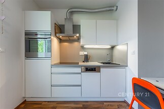 Moderní kuchyň s parketovou podlahou, vestavěnými spotřebiči a světlým nábytkem, je ideální pro pohodlné vaření v moderním stylu.