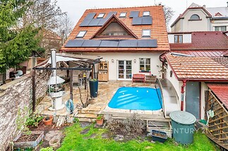 Zahrada s terasou a bazénem, dlážděná podlaha, venkovní krb, moderní úprava.