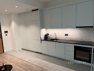 Moderní kuchyň s vestavěnými skříněmi, dlažbou a světlými povrchy, nabízí elegantní design a funkčnost.