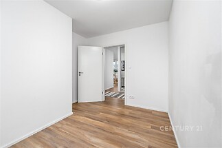 Prázdný pokoj s parketovou podlahou, světlé stěny a moderní dveře, připravený k dekoraci a zařizování podle představ nového majitele.