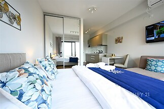 Prostorná ložnice s moderním designem, velkými okny a parketovou podlahou. Vestavěné skříně a světlé barvy dodávají místnosti elegantní vzhled.