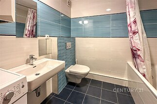 Moderní koupelna s modrou dlažbou, sprchovým koutem a umyvadlem. Světlé obklady dodávají prostoru svěží vzhled.