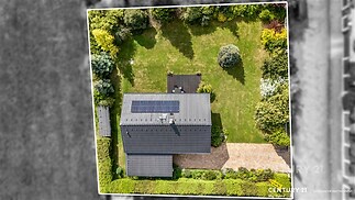 Letecký pohled na zahradu s moderním domem, solární panely, střešní tašky, udržovaný trávník, přírodní prostředí, klidná lokalita.