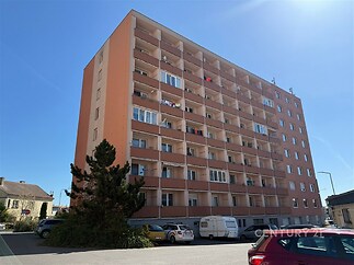 Bytový dům s balkony, panelová konstrukce, slunečné počasí, městská lokalita.