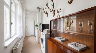 Úzká chodba s parketovou podlahou, velkými okny a úložným prostorem ve venkovském stylu poskytuje světlé a vzdušné prostředí.