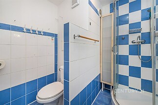 Koupelna s bílými a modrými dlaždicemi, sprchovým koutem a úložnou skříňkou, moderní design.