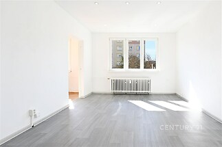 Světlý obývací pokoj s velkými okny, moderní parketová podlaha, bílý strop s vestavěným osvětlením, nově rekonstruovaný stav.