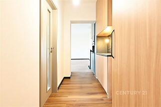 Úzká chodba s parketovou podlahou, dřevěné vestavěné skříně, moderní osvětlení, příjemný světlý design, vchod do otevřeného obývacího pokoje.