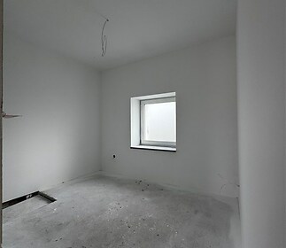 Světlá ložnice s velkým oknem, betonová podlaha připravena k pokládce, čisté bílé stěny, moderní design interiéru.