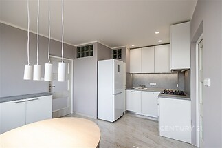 Moderní kuchyň s bílým nábytkem, mramorovou dlažbou a vestavěnými spotřebiči, světlá díky velkým oknům a minimalistickému designu.