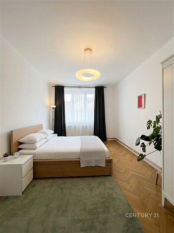 Prostorná ložnice s parketovou podlahou, velkým oknem.