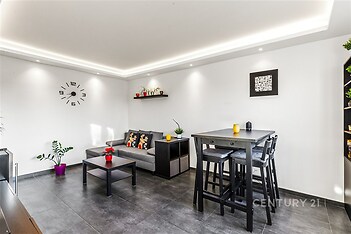 Moderní obývací pokoj, dlážděná podlaha, velká okna, minimalistický design, vestavěné osvětlení, zrekonstruovaný stav, pohodlný nábytek.