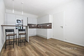 kuchyně s backsplash, ploché panelové skříňky, mikrovlnná trouba, dřevěná podlaha, a bílé skříně