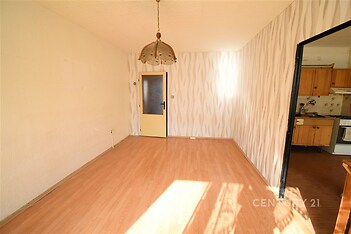 Světlý obývací pokoj s laminátovou podlahou, moderní tapetou a velkým oknem. Propojení s kuchyní pro praktické bydlení.