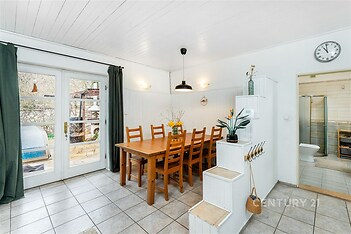 Jídelna s dlažbou, velkými okny a moderním osvětlením. Světlý prostor nabízí přístup na terasu, ideální pro rodinné večeře.