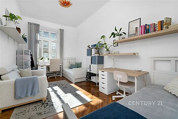 Dětský pokoj s parketovou podlahou, velkými okny a moderním vybavením. Světlý prostor s vestavěnými skříněmi a pracovním stolem.