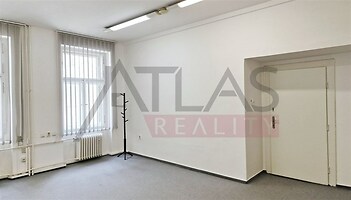 Světlá místnost s velkými okny, kobercovou podlahou a bílými stěnami, vhodná pro kancelářské využití, ve velmi dobrém stavu.