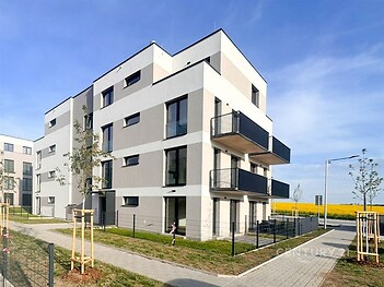 Moderní bytový dům s balkony, minimalistická architektura, kvalitní fasádní úpravy, klidná lokalita s upraveným okolím v blízkosti přírody.