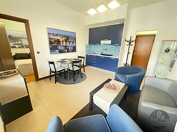 Moderní obývací pokoj s dlažbou, vestavěnou kuchyní a jídelním koutem, světlý a vkusně zařízený se stylovým nábytkem.