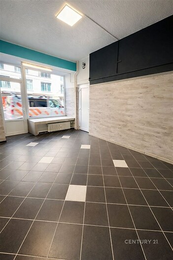 Světlý komerční prostor s dlažbou a velkými okny, moderní interiér s bílými stěnami a dostatkem přirozeného světla, ideální pro obchod.