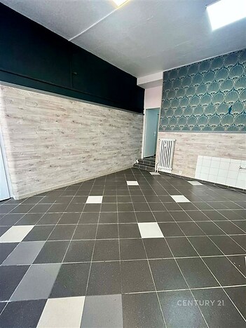 Prostor s dlažbou a dekorativní tapetou, vhodný pro rekonstrukci. Světlé stěny a designový prvek nabízí moderní možnosti využití.