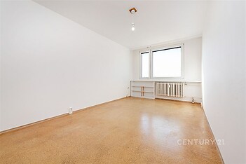 Prázdná ložnice s bílými stěnami, světlé lino, velká okna, topení u okna, dostatek přirozeného světla, moderní vzhled, čistý prostor