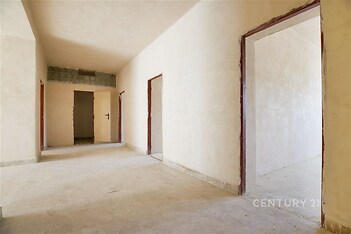 Chodba s betonovou podlahou, přístupem do pokojů, světlá výmalba, vhodná pro rekonstrukci či modernizaci, prostorný interiér.