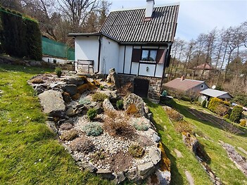Kompaktní venkovský dům s kamennými prvky a zahradní skalka. Umístěný v malebné krajině, ideální pro rekreaci.