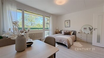 Světlá ložnice s velkými okny, moderním nábytkem a parketovou podlahou nabízí pohodlné a stylové bydlení.