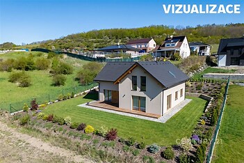 Rodinný dům s moderní fasádou, dřevěnou terasou a pečlivě udržovanou zahradou, obklopený přírodou a klidnou lokalitou.