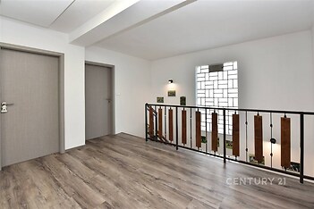 Chodba s moderním laminátovou podlahou a stylovým zábradlím, dveře v neutrálním odstínu, prostorný a světlý interiér.