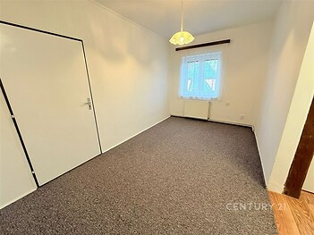 Světlá ložnice s kobercovou podlahou, velkými okny a moderním světlým interiérem, ideální k rekonstrukci či okamžitému nastěhování.