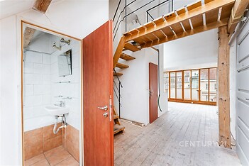 Světlý mezonet s dřevěnou podlahou, velkými okny a moderním schodištěm, který nabízí výhled na město a prostorný interiér.