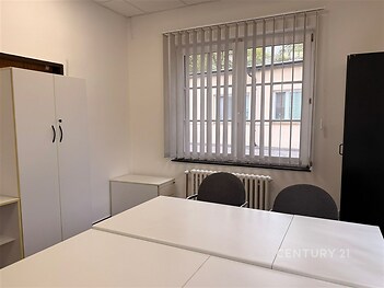 Kancelářský prostor s bílými stoly a židlemi, vestavěné skříně, velká okna se žaluziemi, moderní interiér, vhodný pro podnikání