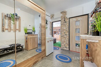 Vstupní hala s dlažbou a vestavěným zrcadlem, moderní dřevěný design, kamenné obložení na stěnách, světlý a vkusně zařízený prostor.