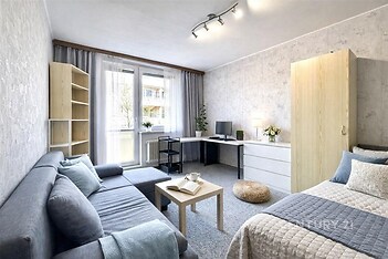 Světlý obývací pokoj s přímým vstupem na balkon, moderní nábytek, světlá parketová podlaha a velká okna zajišťující přirozené osvětlení.