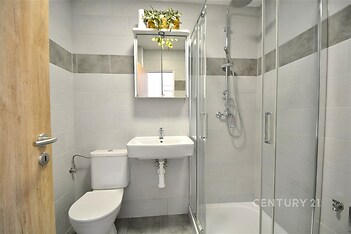 Moderní koupelna s dlažbou, sprchový kout a zrcadlová skříňka, světlé obklady, elegantní design.