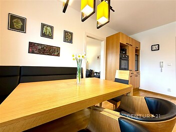 Jídelna s dřevěným stolem a parketovou podlahou, moderní vestavěné skříně a světlé osvětlení, elegantní designový styl.