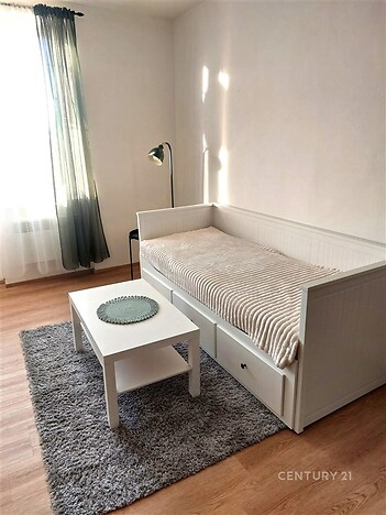 Světlý obývací pokoj s parketovou podlahou, velkými okny a moderním nábytkem.