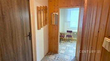 Vstupní chodba s dřevěným obložením, keramická dlažba s geometrickým vzorem a zrcadlo, které opticky zvětšuje prostor.