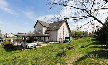 Rodinný dům s moderní fasádou a taškovou střechou, prostorná zahrada s garážovým stáním, klidná rezidenční lokalita.