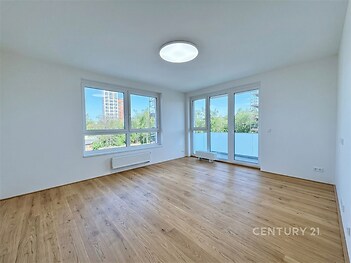 Světlý obývací pokoj s parketovou podlahou a velkými okny, moderní design, výhled do zeleně, ideální prosvětlený prostor k relaxaci