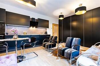 Moderní kuchyň s parketovou podlahou, vestavěné skříně a elegantní osvětlení, stylový a světlý interiér